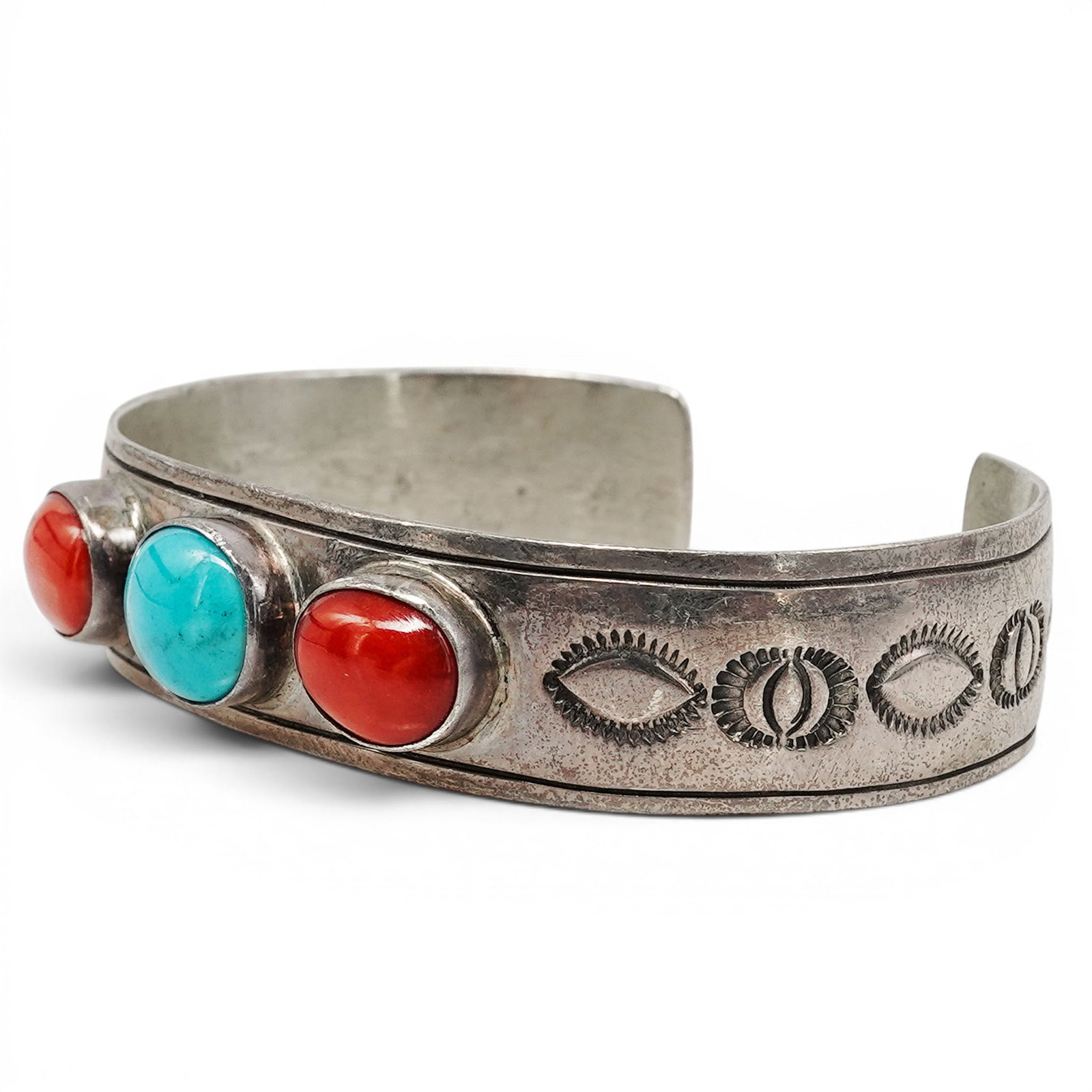 A Nelson Garcia Kewa Sterling Silver, Turquoise, And Coral Cuff Bracelet: A Nelson Garcia Kewa sterling silver, turquoise, and coral cuff bracelet Late 20th Century Stamped: N.G. / Sterling. A tapered cuff bracelet set with a central turquoise cabochon flanked by two coral 
