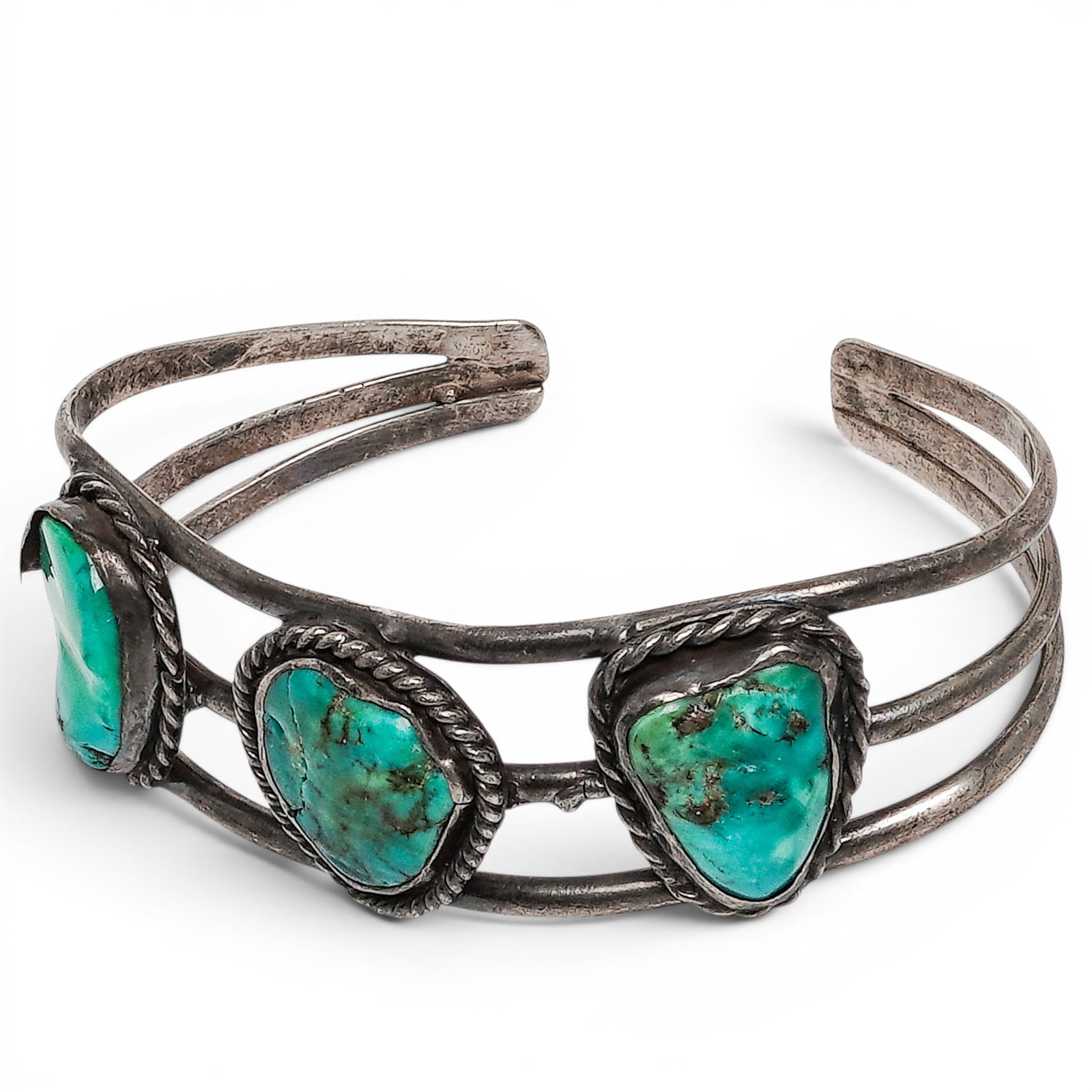 A Navajo Sterling Silver And Turquoise Three Stone Cuff Bracelet: A Navajo sterling silver and turquoise three stone cuff bracelet Late 20th century Unmarked. Tested sterling silver. A split shank cuff bracelet set with three freeform turquoise cabochons in rope wir