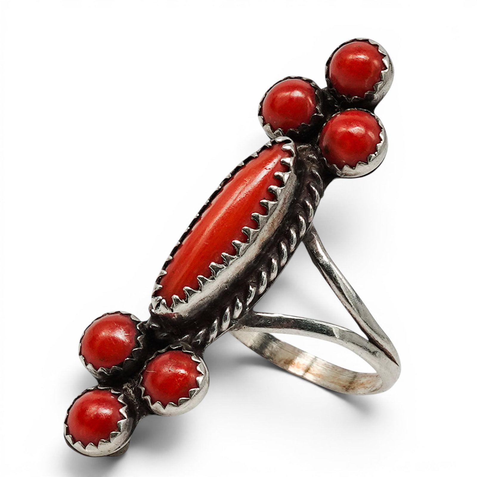 A Navajo Sterling Silver And Coral Cluster Ring: A Navajo sterling silver and coral cluster ring Late 20th century Unmarked. Tested sterling silver. A vertical cluster-form ring set with a central elongated coral cabochon surrounded by six round cor