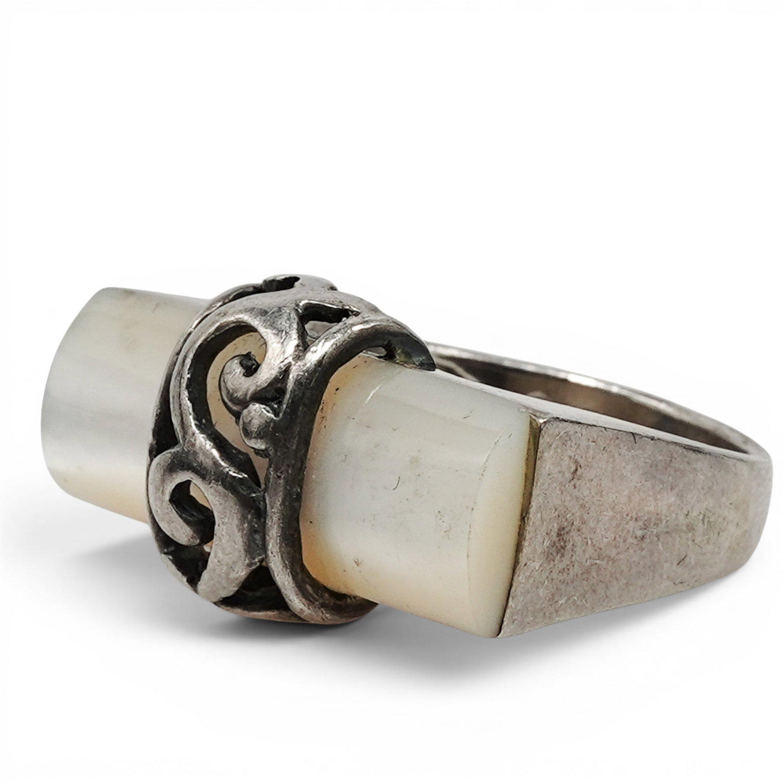 A Navajo Sterling Silver And MOP Scrollwork Ring: A Navajo sterling silver and MOP scrollwork ring Late 20th century Stamped: .925. A ring set with a rectangular mother of pearl bar, framed by openwork scroll motifs and mounted on a tapered silver sh