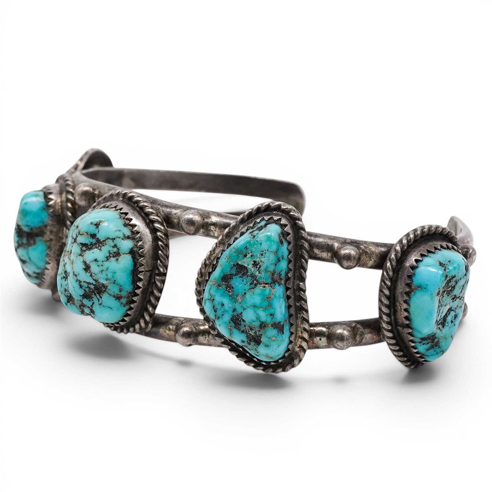 A Navajo Sterling Silver And Turquoise Five Stone Cuff Bracelet: A Navajo sterling silver and turquoise five stone cuff bracelet Late 20th Century Unmarked. Tested sterling silver. A cuff bracelet set with five oval turquoise cabochons in rope wire bezels, joined b