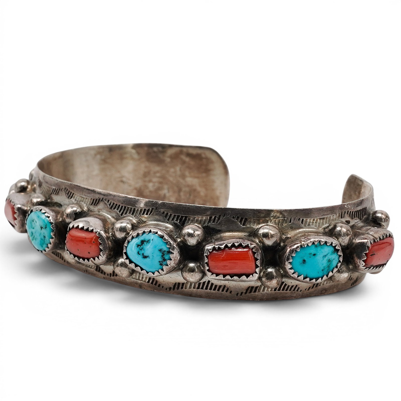 A Navajo Sterling Silver, Turquoise, And Coral Row Cuff Bracelet: A Navajo sterling silver, turquoise, and coral row cuff bracelet Late 20th century Stamped: Sterling. A cuff bracelet with alternating turquoise and coral cabochons in serrated bezels, accented by app