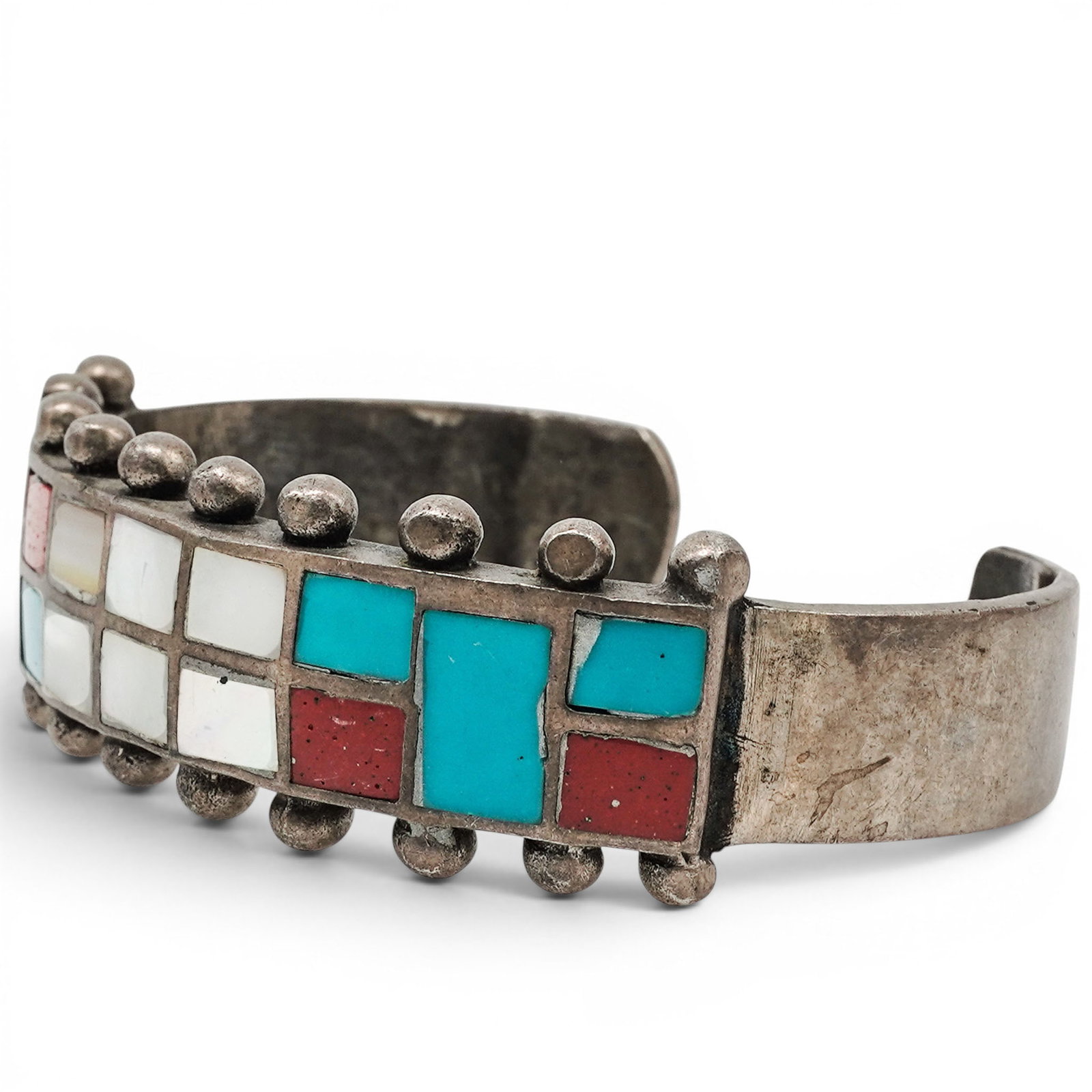 A Navajo Sterling Silver And Multistone Channel Inlay Cuff Bracelet: A Navajo sterling silver and multistone channel inlay cuff bracelet Late 20th century Unmarked. Tested sterling silver. A cuff bracelet with geometric channel inlay incorporating turquoise, coral, mot