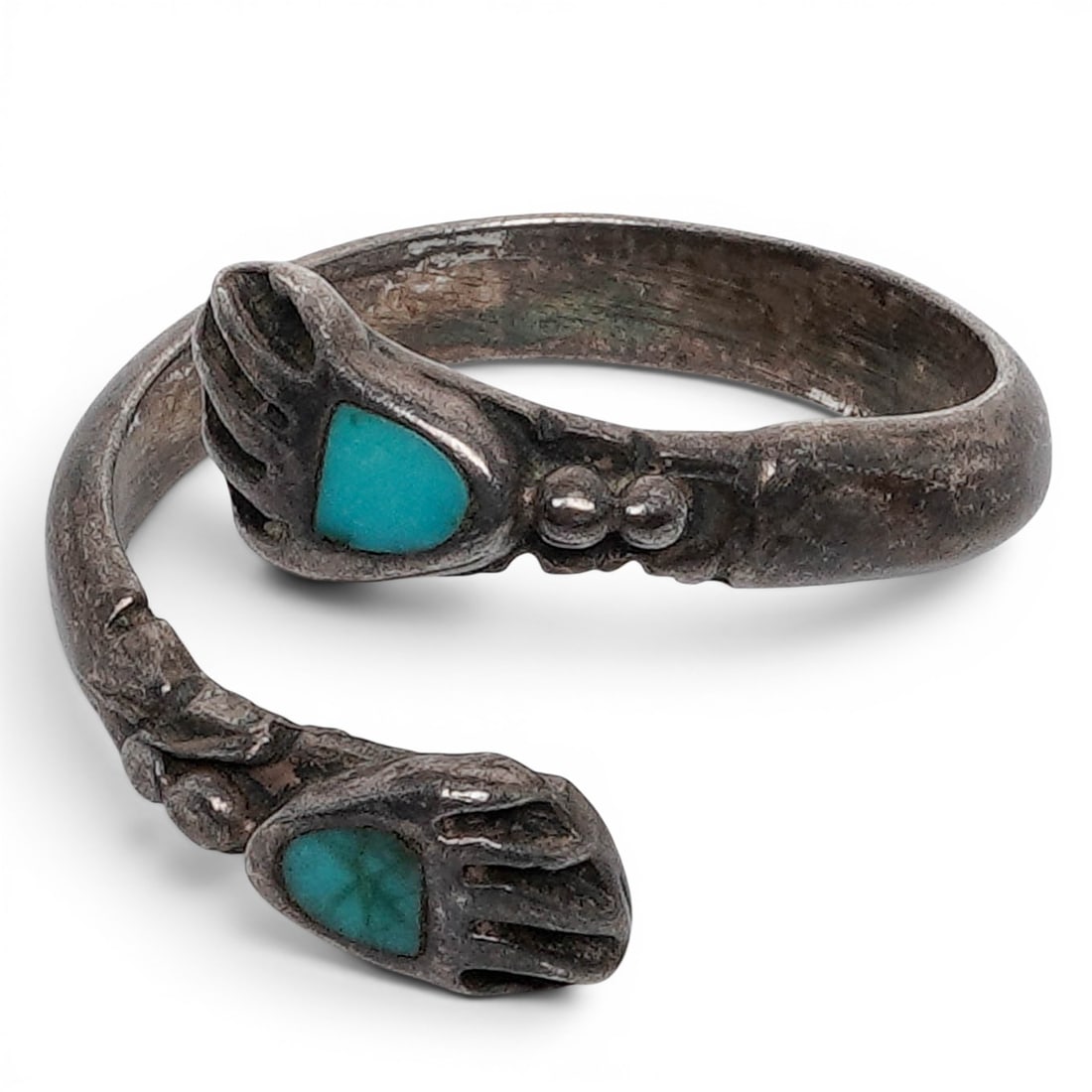 A Navajo Sterling Silver And Turquoise Hand Motif Bypass Ring: A Navajo sterling silver and turquoise hand motif bypass ring Late 20th century Unmarked. Tested sterling silver. A bypass ring terminating in two stylized hand motifs, each set with a triangular turq