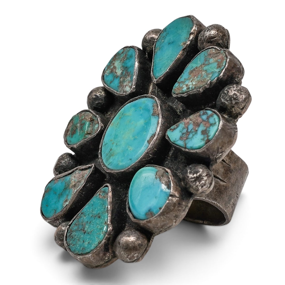 A Navajo Sterling Silver And Turquoise Cluster Ring: A Navajo sterling silver and turquoise cluster ring Late 20th century Unmarked. Tested sterling silver. A large cluster ring with central oval turquoise cabochon surrounded by nine turquoise cabochons