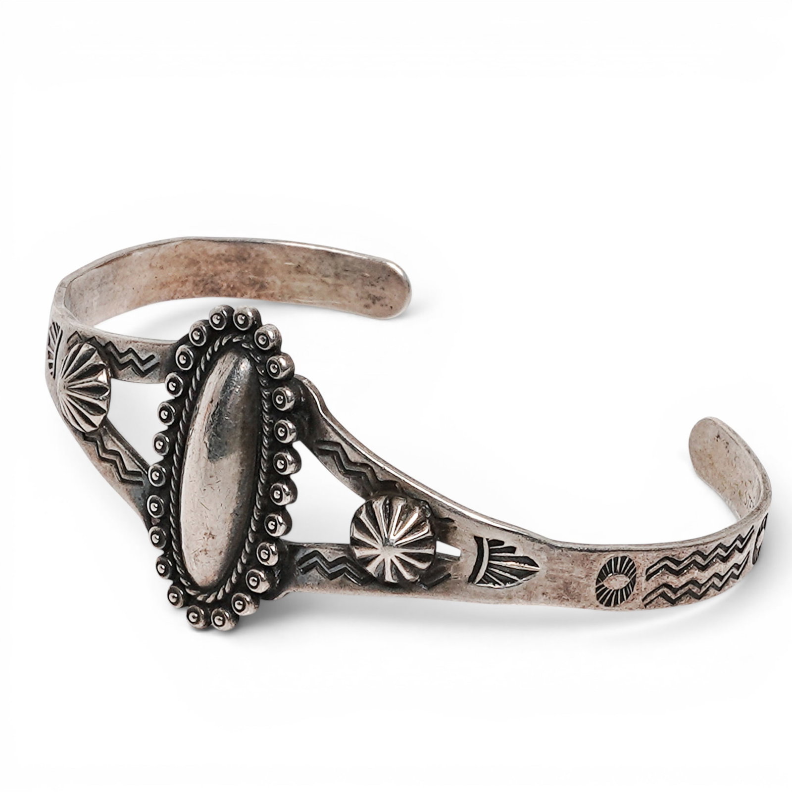 A Navajo Sterling Silver Stamped And Beaded Cuff Bracelet: A Navajo sterling silver stamped and beaded cuff bracelet Late 20th Century Stamped: Sterling. A tapered silver cuff with central oval domed mount surrounded by applied silver beads, with stamped deco