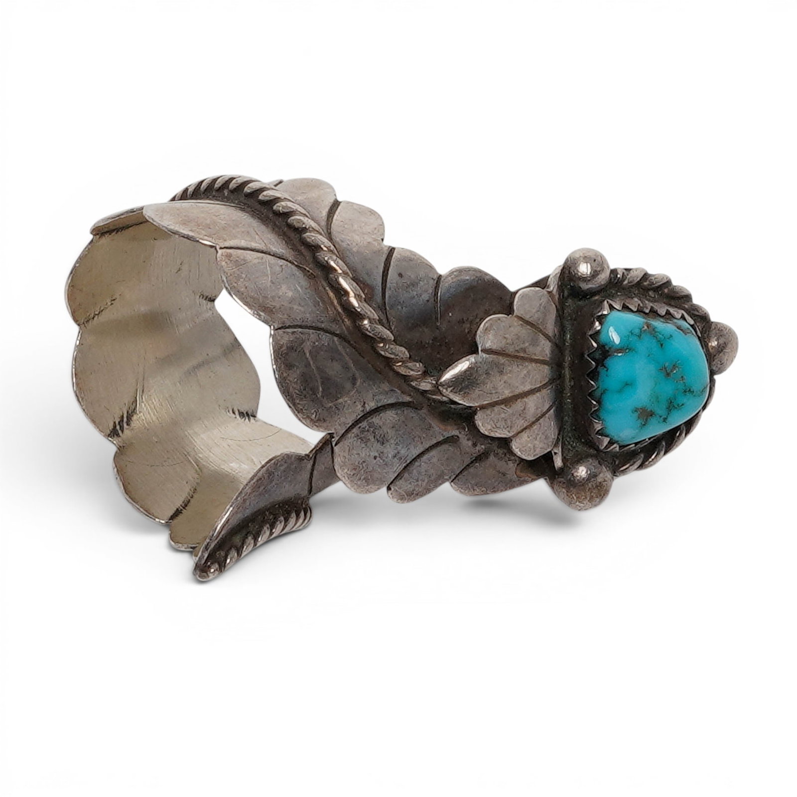 A Randall Endito Navajo Silver And Turquoise Leaf Ring: A Randall Endito Navajo silver and turquoise leaf ring Late 20th century Stamped: E / Sterling. A ring set with an oval turquoise cabochon in a serrated bezel mount, accented with applied leaf motifs,