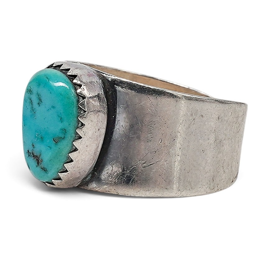 A Navajo Sterling Silver And Turquoise Wide Band Ring: A Navajo sterling silver and turquoise wide band ring Late 20th century Unmarked. Tested sterling silver. A wide tapering silver band ring centered by an oval bezel-set turquoise cabochon in a serrate