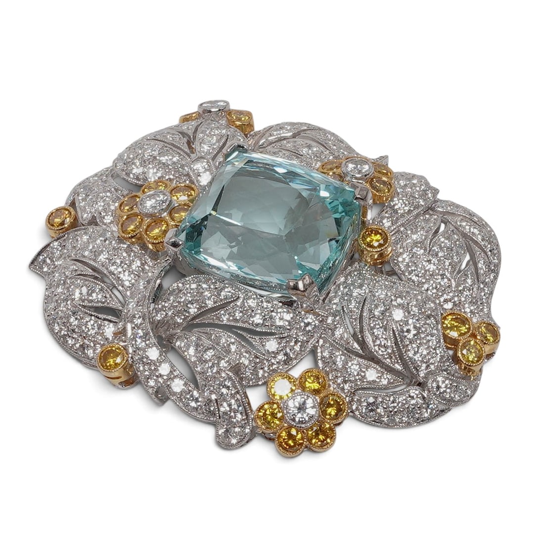 18K Gold Aquamarine Yellow Sapphire & Diamond Floral Brooch: 18K Gold Aquamarine Yellow Sapphire & Diamond Floral Brooch Late 20th Century 18K white and yellow gold floral and foliate brooch with a large cushion-cut aquamarine and pavé-set white VS+ quality di