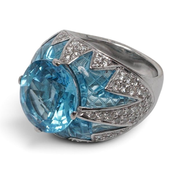 18K Gold Blue Topaz & Diamond Cocktail Ring: 18K Gold Blue Topaz & Diamond Cocktail Ring Contemporary 18K white gold cocktail ring designed with a large oval faceted blue topaz center, angular carved blue topaz side panels, and pavé-set diamond