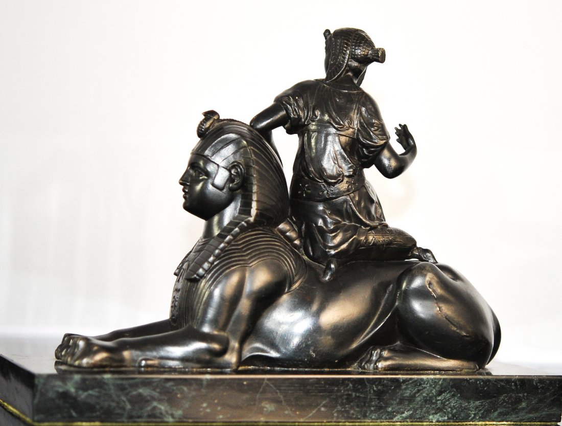 19th Centuary French Bronze In a Egyptain Motif: DESCRIPTION: Late 19th centuary french bronze featuring a woman lightly seated upon a sphinx ontop of a rectangularlar marmo verde antico base. Has meticulous detail in design with egyptian attributes