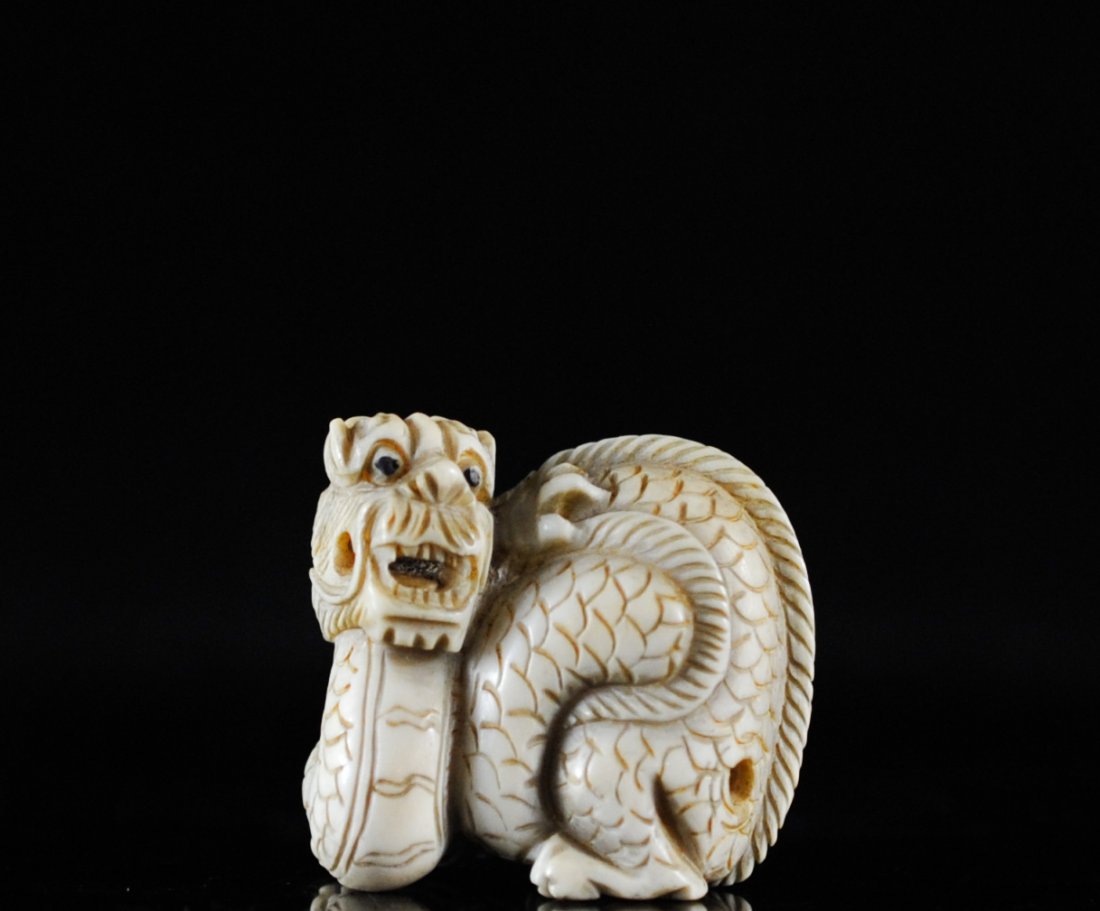 Antique Hand Carved Ivory Dragon Netsuke: DESCRIPTION: Early Chinese hand carved dragon netsuke. Features a long slender dragon carving which is balled up tightly as to protect itself. Wonderful piece with superb engravings. Slight aged patin