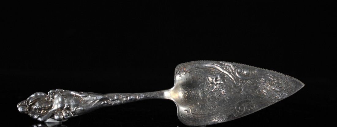 Antique Sterling Silver Serving Cake Knife: DESCRIPTION: Sterling silver serving cake knife featuring a floral motif along the blade and handle. Handle is finished with a unique baroque style design of a posing woman. Hallmarked on back "Sterli