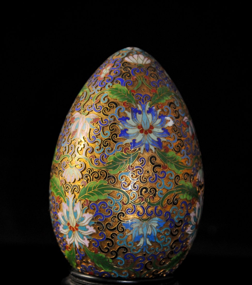 Large Chinese Cloisonne Gold Egg: DESCRIPTION: Large cloisonne gold egg, Enameled with amazing detail. Floral design throughout. Sitting on a wooden stand. Perfect condition. CIRCA: 20th century ORIGIN: China DIMENSIONS: H 7'' ; W 4"