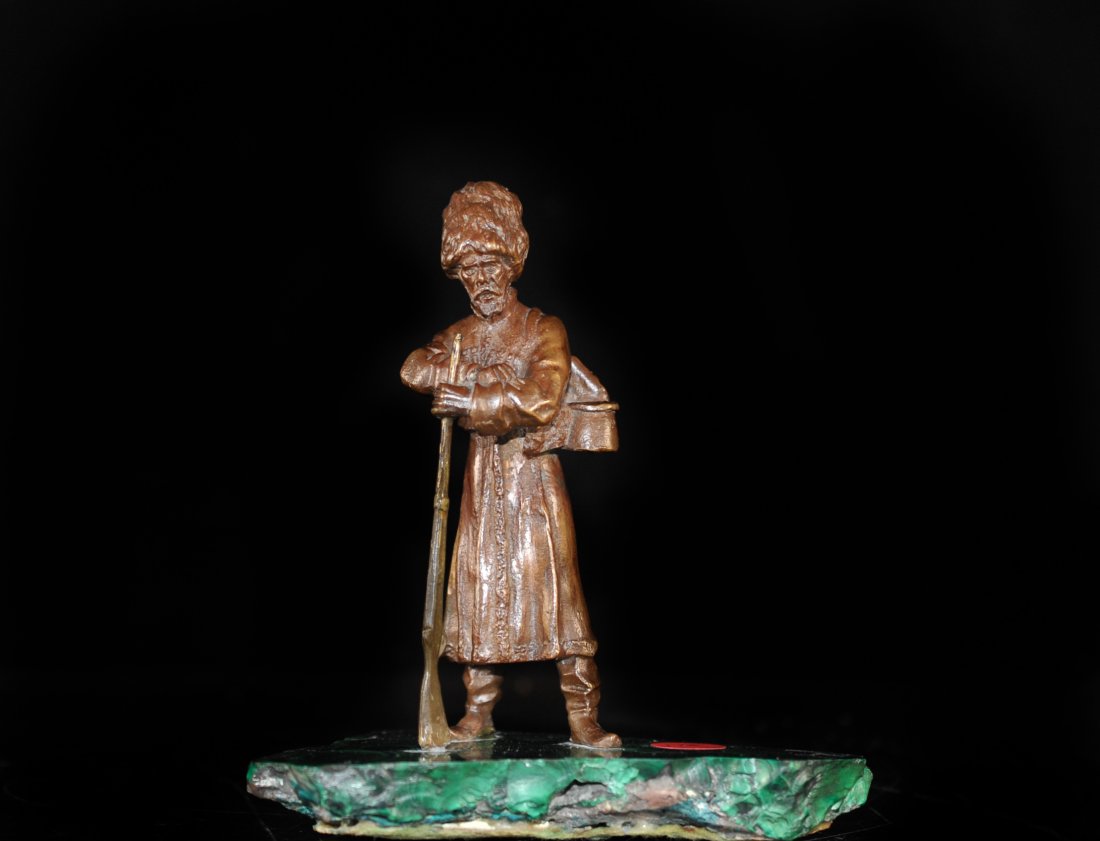 Antique Russian Bronze Sculpture: DESCRIPTION: Bronze sculpture sitting on a malachite base. Depicting a russian hunter or soldier leaning on a rifle. Great patina showing clothing and backpack with supplies. CIRCA: 20th century ORIGI