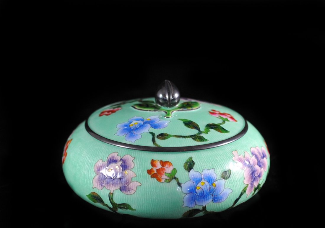 Japanese Silver Enamel Circular Box: DESCRIPTION: Japanese silver enamel circular box featuring light green background. Decorated with multi-colored floral enamel along the body and lid. Finial is in shape of a flower bulb. Weight 137 gr