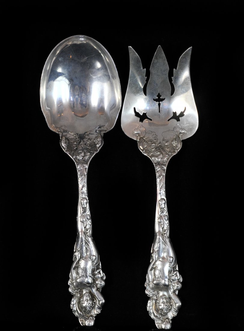Reed & Barton Sterling Silver Serving Utensils: DESCRIPTION: Set of two sterling silver serving fork and spoon. Fork and spoon feature a baroque design along the handle, finished with a dipiction of a woman with her baby. Hallmarked with "Sterling"