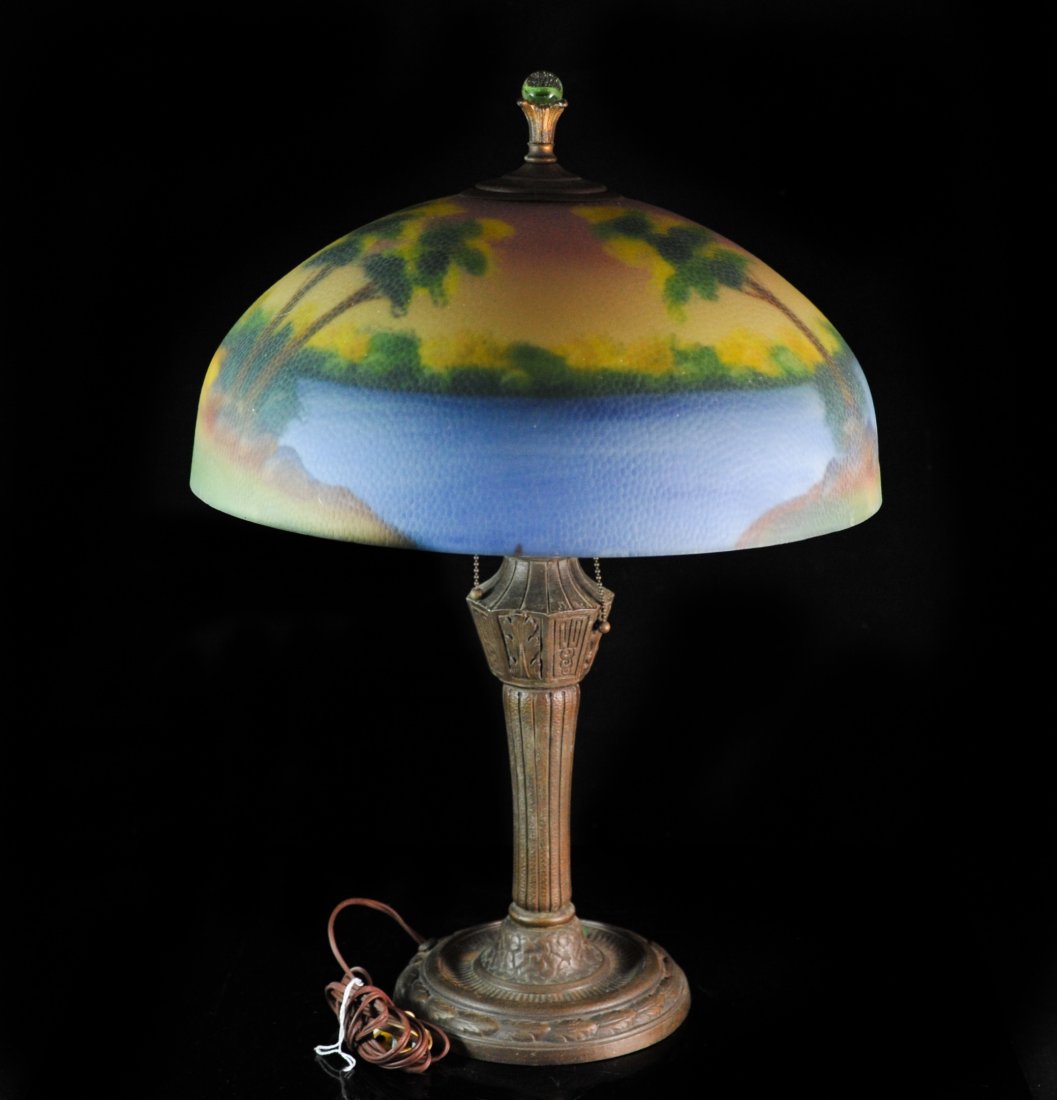 Art Nouveau "Handel Budior" Table Lamp: DESCRIPTION: Handel Budior Lamp supporting a reverse painted glass shade. Glass shade features a tropical landscape scene with trees and water. Lamp supported by metal standing base with a glass marbl