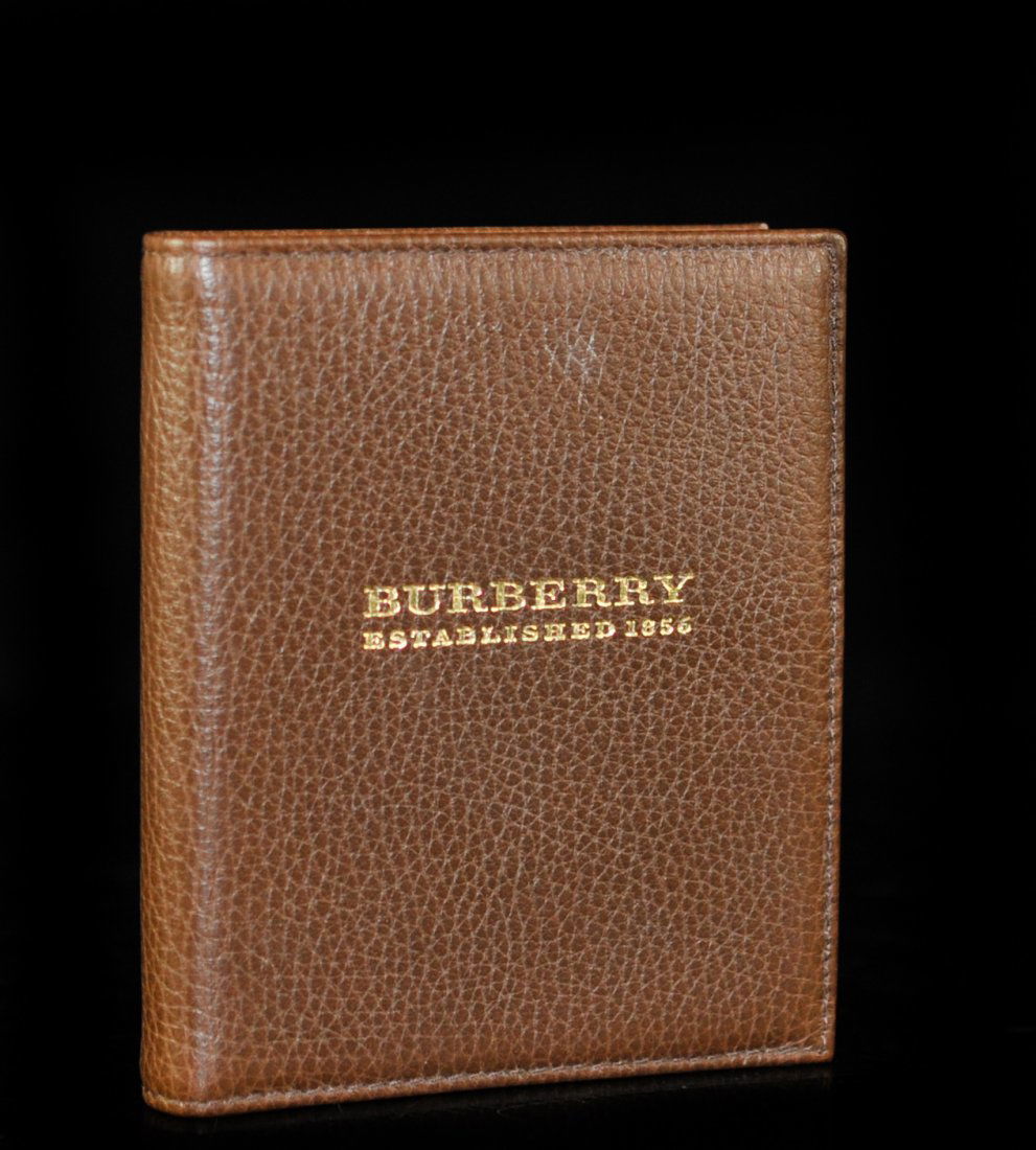 Burberry Dark Brown Leather Notebook: DESCRIPTION: Burberry dark brown pebbled leather notebook. Features gold embossed Burberry logo on front and unlined pages. Back marked "Burberry Made in Italy". Couple of pages ripped out. CIRCA: 20t