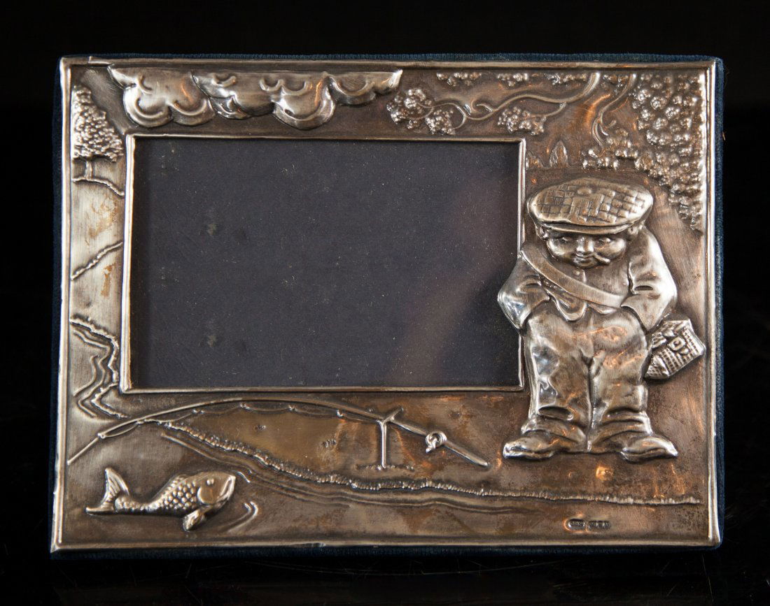 Vintage Sterling Silver Picture Frame: DESCRIPTION: Vintage sterling silver embossed picture frame of a man carrying a bad and coy fish on the lower left, blue velvet back. Traditional English Hallmarked on the bottom right corner. CIRCA: