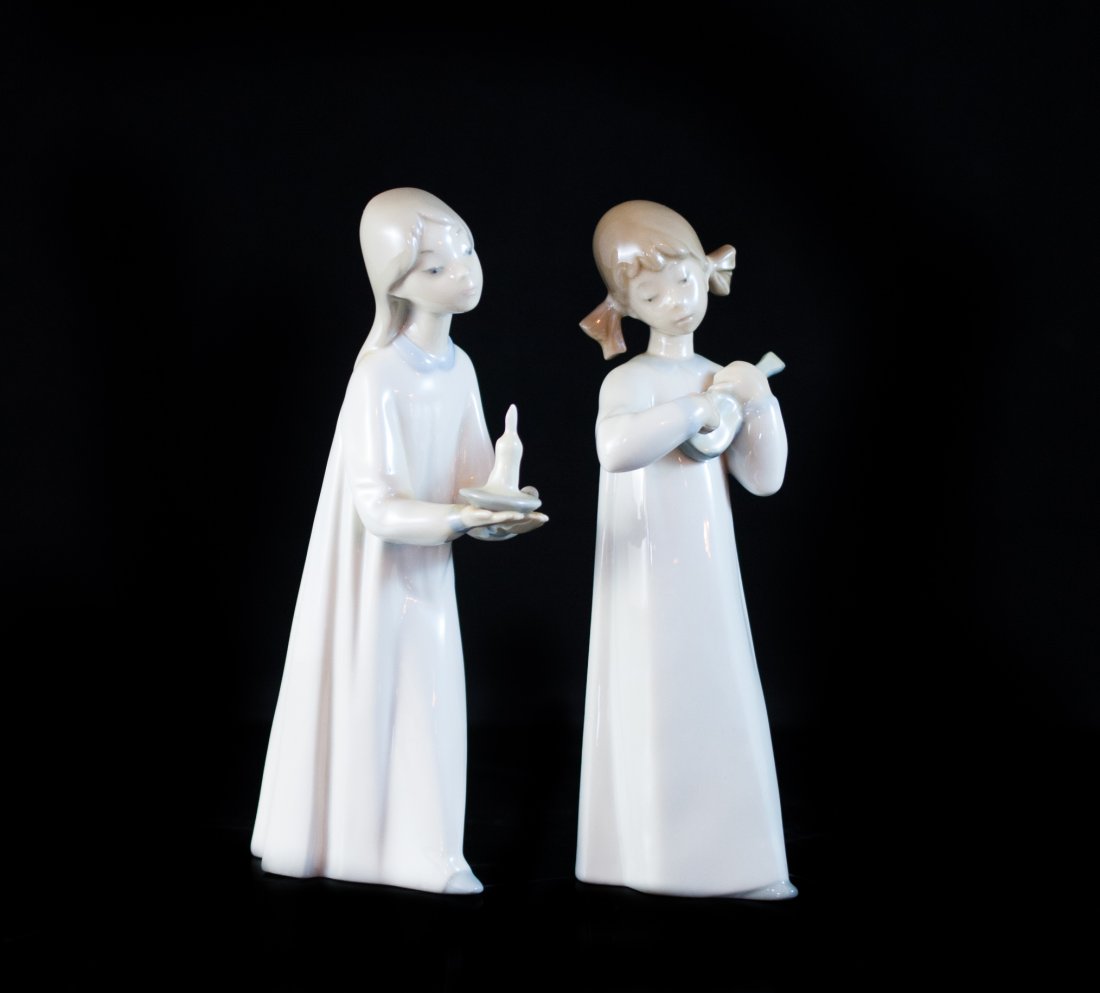 Pair Of Lladro Figurines: DESCRIPTION: Pair of Lladro figurines depict two young girls draped in pajamas. One stands holding a candle while the other has a small instrument. Marked on the bottom "Lladro Made In Spain" CIRCA: m