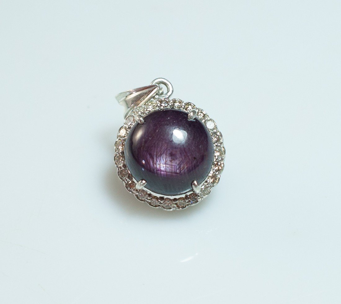 Silver Diamond & Star Ruby Pendant: DESCRIPTION: Sterling silver pendant features a large round star ruby, with a beautiful and unique color carefully placed in the center. Surrounding the ruby are small diamonds amounting to approximat