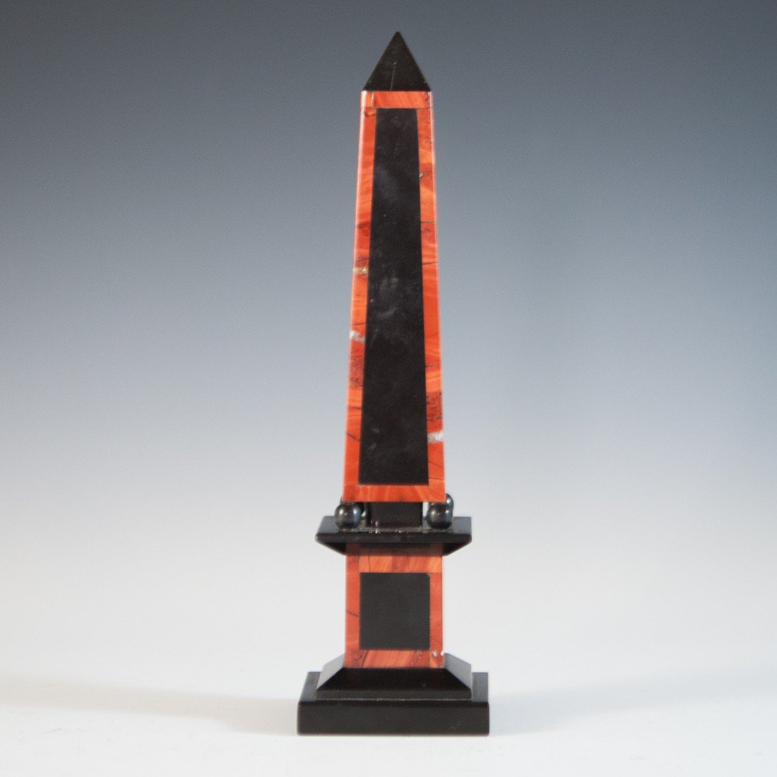 Onyx Miniature Obelisk: DESCRIPTION: Onyx obelisk features a black pillar onyx bordered by red malachite elegantly sits on four spheres, then mounted on a column base. CIRCA: Early 20th Ct. DIMENSIONS: H: 8" L: 2"