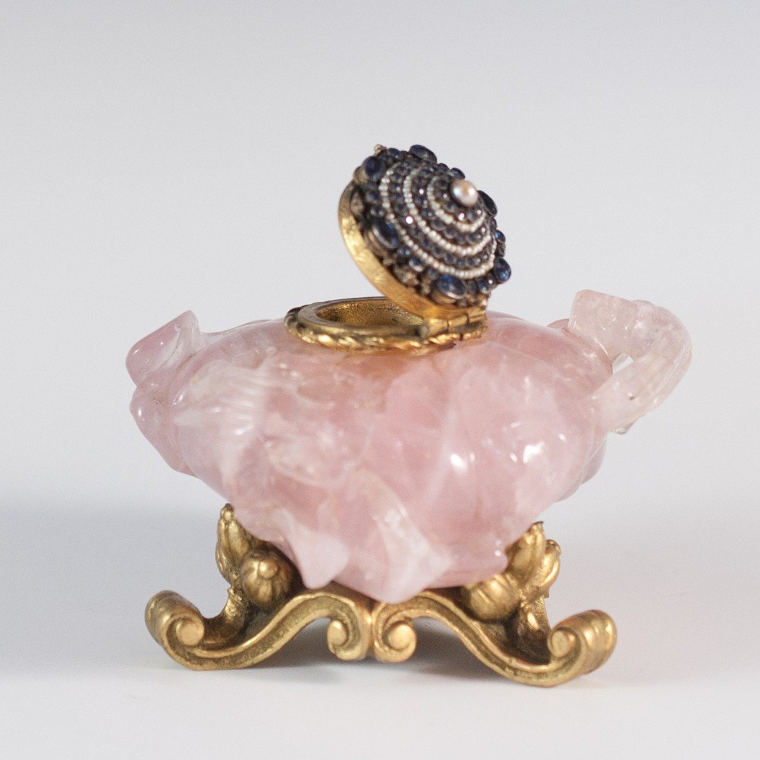 Nicholas Hayden Quartz & Sapphire Inkwell: DESCRIPTION: Rose quartz inkwell crafted and carved by Nicholas Hayden features a gilded figural bronze base and top , the top is covered in natural sapphires alternating with layers of mother of pear