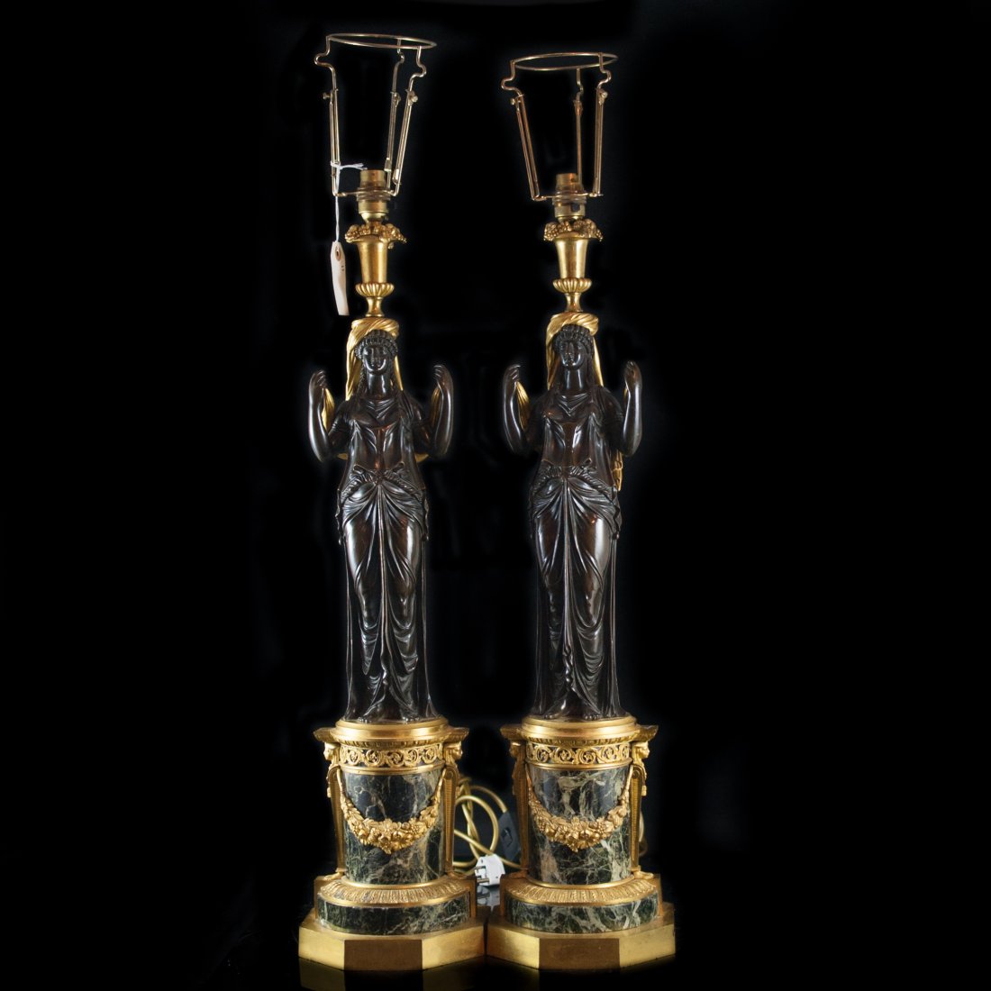 Imperial Gilded Bronze & Marble Candle Sticks: DESCRIPTION: Pair of imperial bronze candle sticks feature two tones of gilded and dark brown patina. Each candle stick depicts a grace draped in robes standing on a black marble base with bronze oran