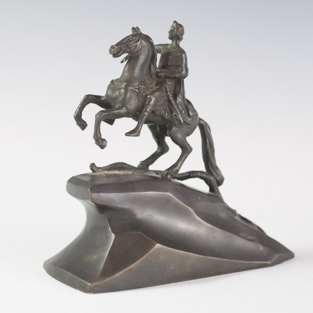 Man on Horse Bronze Figurine: DESCRIPTION:Bronze figurine of a regal Greco-Roman soldier mounted on a galloping horse that is stomping on a serpent. Fixed upon a bronze hill base. CIRCA:20th Ct. ORIGIN:Italy DIMENSIONS:H:5" L:5" W