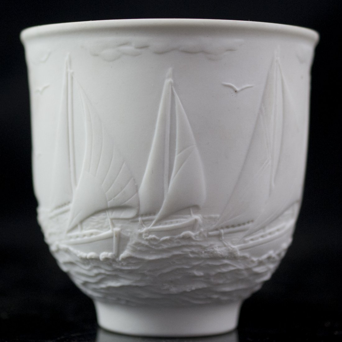 Lladro Collectors Society Porcelain Cup: DESCRIPTION:Lladro collectors society porcelain cup. Features embossed illustrations sail ships away at sea surrounded by white capped waves, seagulls, and clouds. Marked on bottom:"Collector's Societ