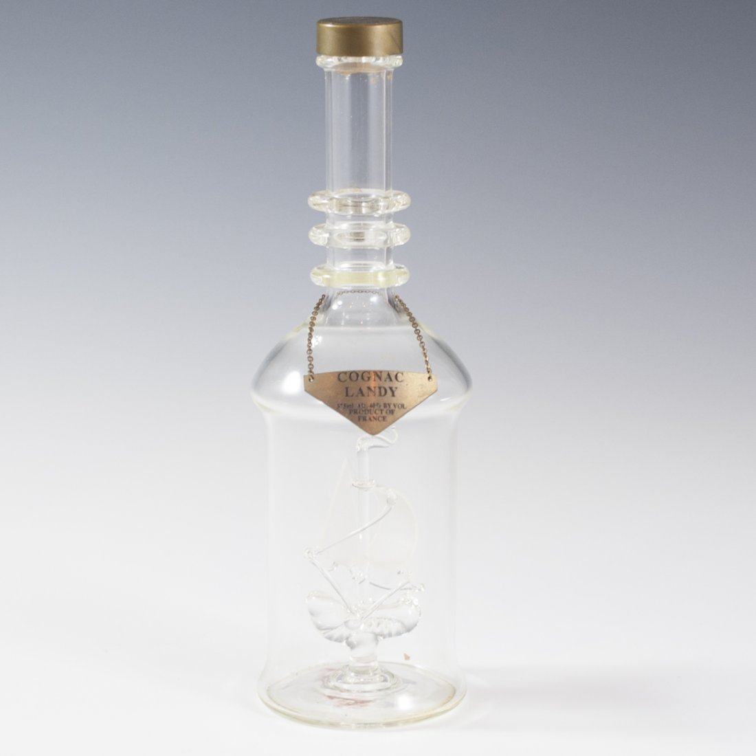 Cognac Landy Bottle With Ship: DESCRIPTION:Cognac Landy bottle finished with a small ship in the interior. Fitted with a chained mount that reads:"Cognac Landy 375Ml Alco 40% by Vol Product of France" CIRCA:20th Ct. ORIGIN:France D