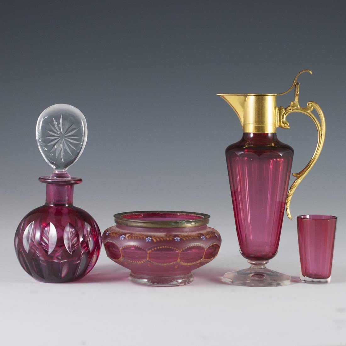 Cranberry Glass Assortment: DESCRIPTION: Cranberry glass assortment comprising of: an ashtray frosted glass accents and enameled floral motif, a small perfume bottle intricate oval cuts and clear cut glass stopper, a thimble sho