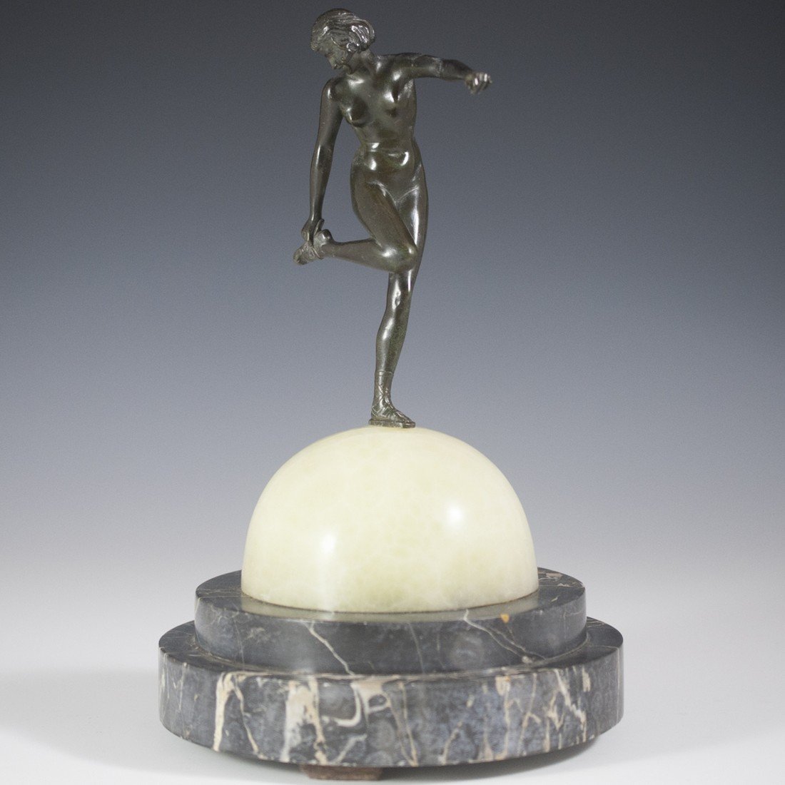 Pierre Le Faguays (French 1892 - 1962): DESCRIPTION: Art Deco bronze by Pierre Le Faguays, whose other names include: Raymonde Guerbe and Pierre Lefaguays. Features an elegant nude woman tying her gladiator sandals while standing atop a dem