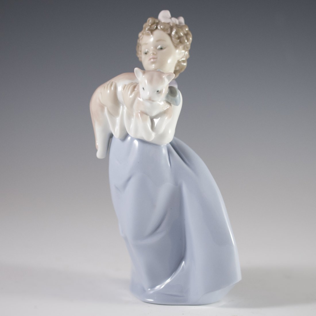 Lladro Porcelain Figurine: DESCRIPTION: Lladro porcelain figurine of a young girl in a dress, holding a kitten with bow hands. Finished with a glossed glaze and marked on bottom:"Lladro 97 OG Hand Made in Spain DAISA 1996" CIRC