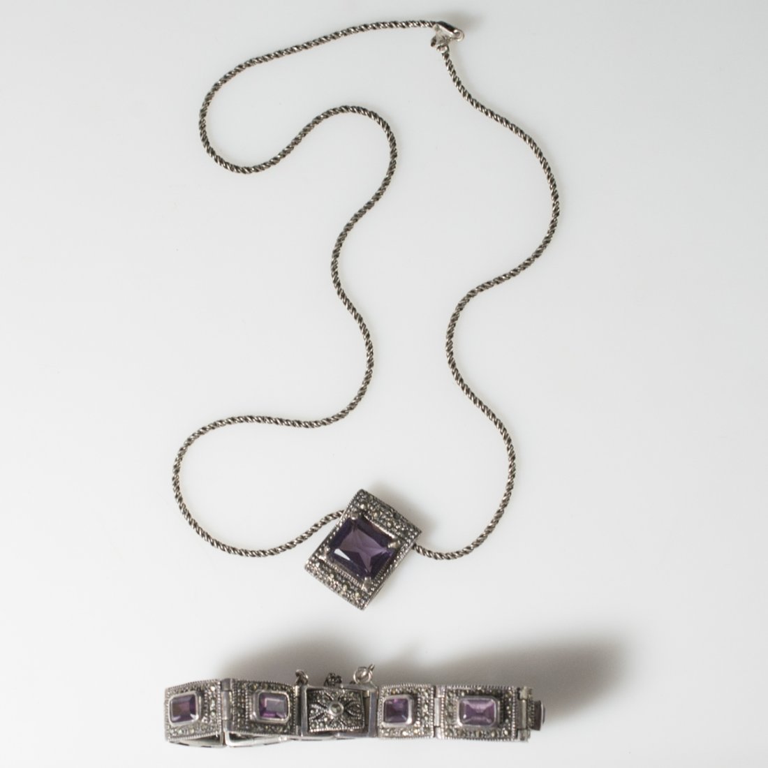 Sterling Amethyst & Marcasite Jewelry Set: DESCRIPTION: Sterling jewelry set comprising of a necklace and pendant, and a bracelet. The necklace features a coiled rope chain and a pendant with a prong set amethyst stone surrounded by faceted ma