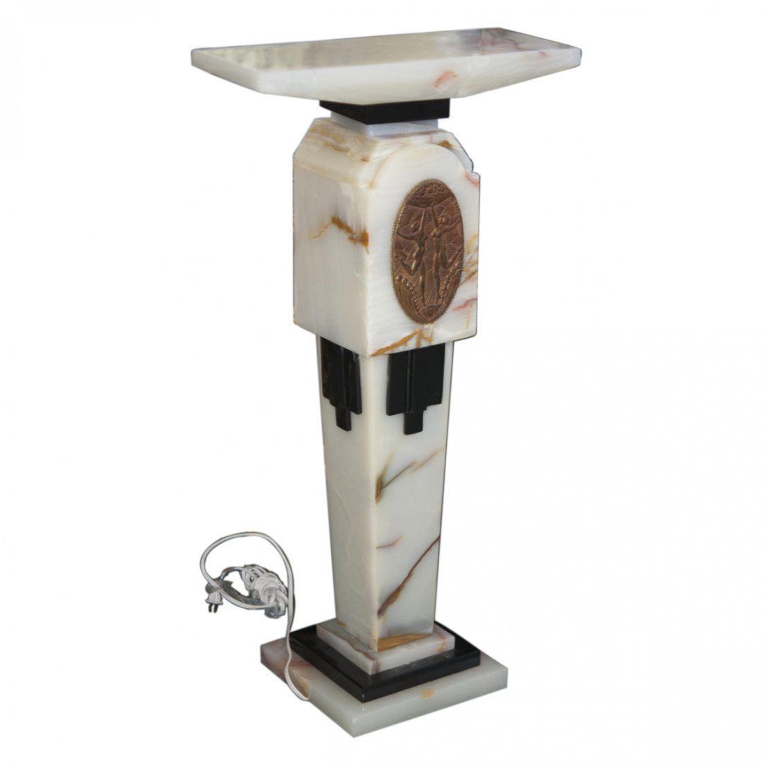 After Demetre Chiparus (Romanian 1886-1947) Pedestal: DESCRIPTION: An Art Deco style onyx pedestal after Demetre Chiparus. Features overall white onyx with black onyx accents. Finished with a bronze plaque along the center of the stem with embossed rende