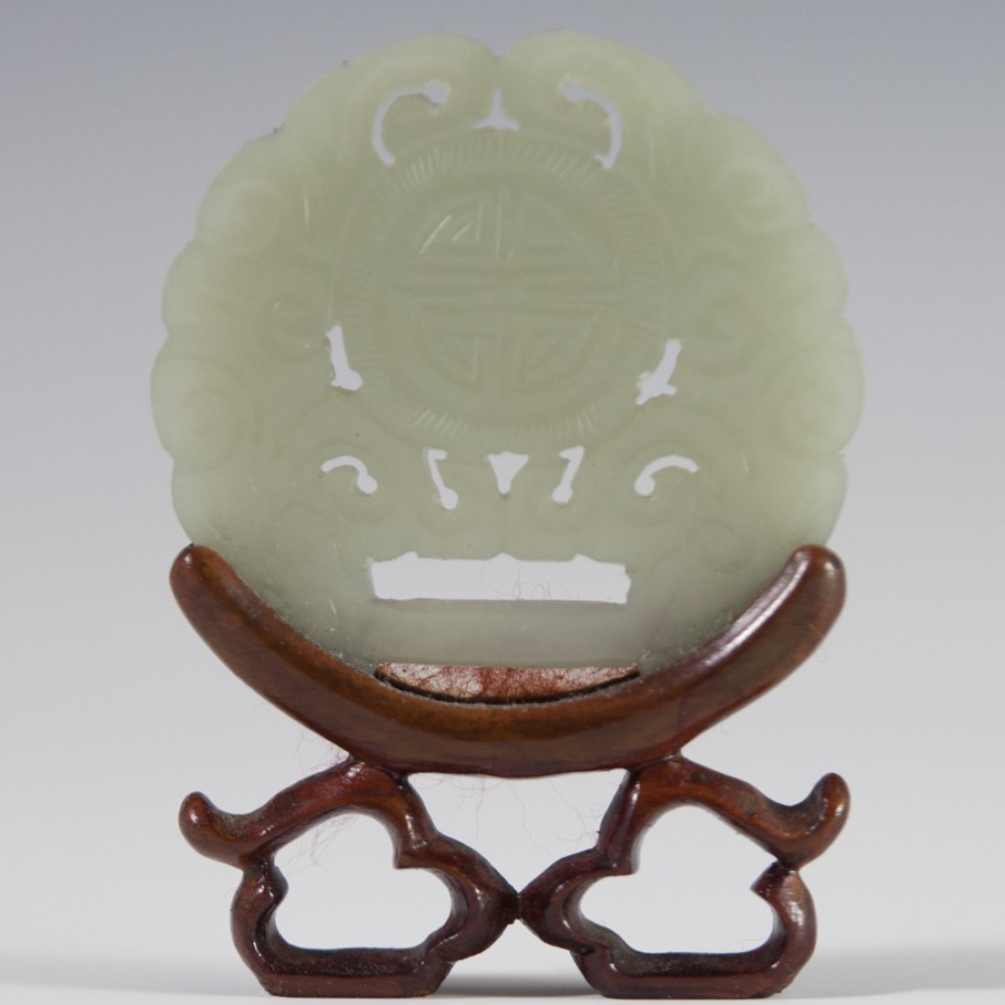 Carved Jade Medallion: DESCRIPTION: A carved jade medallion featuring intricate coiled reticulations and engravings along with traditional chinese patterns. Fitted to a wooden base. CIRCA: 20th Ct. ORIGIN: China DIMENSIONS:
