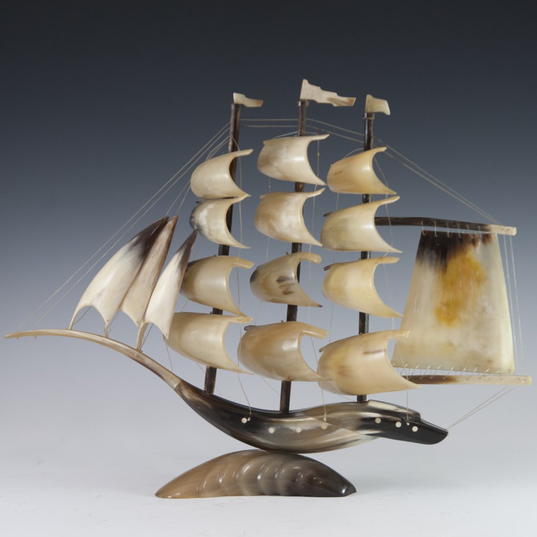 Ram Horn Sailboat Model: DESCRIPTION: A model sailboat comprised of ram horn along the base, hull, flags, and sails. Held together by acrylic string and inlaid with dotted accents. CIRCA: 20th Ct. ORIGIN: Unknown DIMENSIONS:H