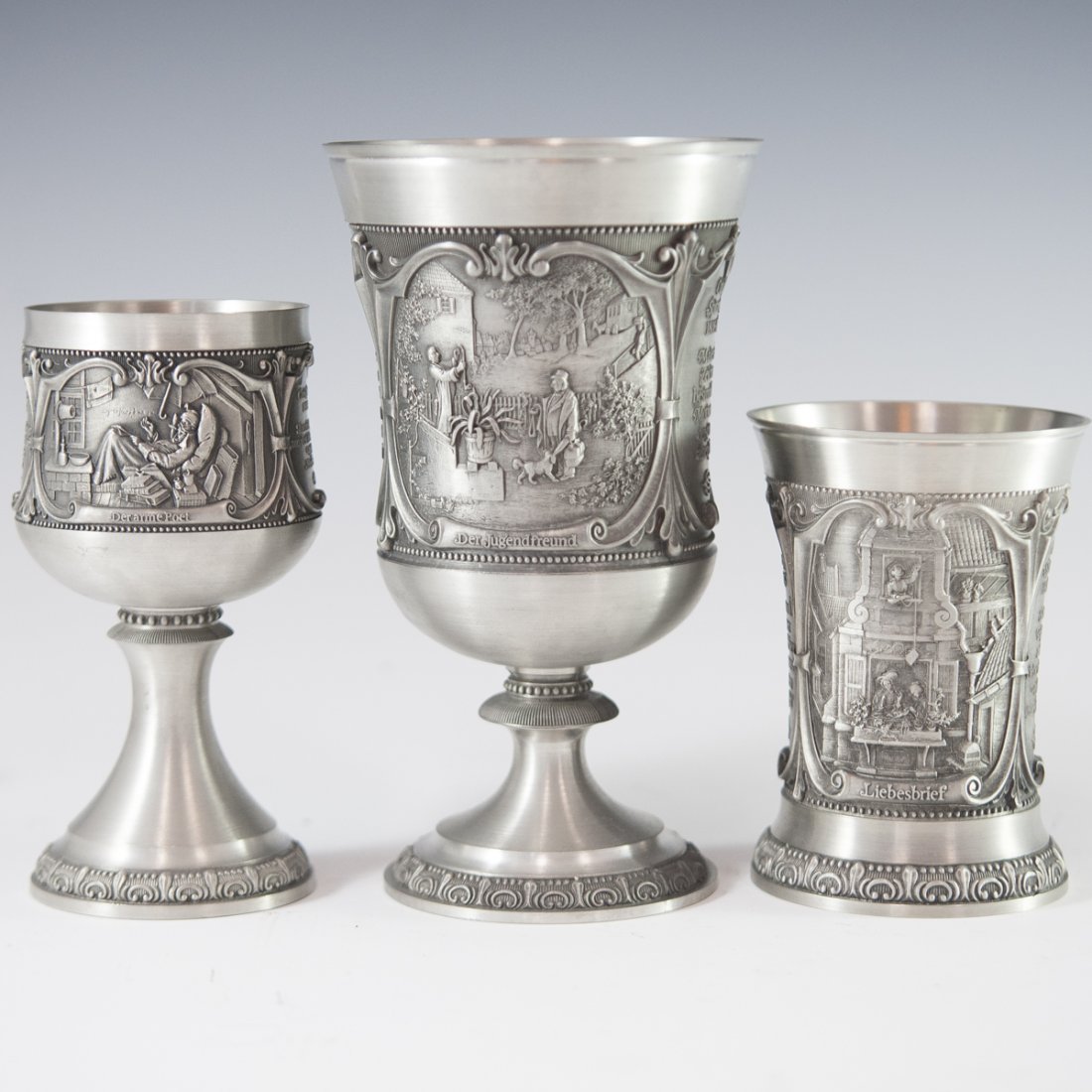 Vintage WMF Pewter Chalices: DESCRIPTION: Vintage WMF pewter chalices dedicated to famous German Painter, Carl Spitzweg. Features a goblet, a cup, and a wine cup. All are embellished with embossed scenes of his artwork as well as