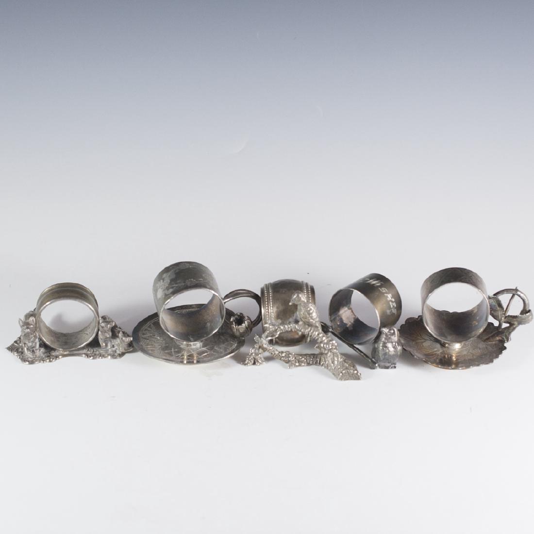 Silver Plated Napkin Rings: DESCRIPTION:Set of five silver plated napkin rings. One features a tulip with a spiraling stem as a handle and is marked:"Meriden B Company". One is marked: "Best Wishes" and comprises of a small bird