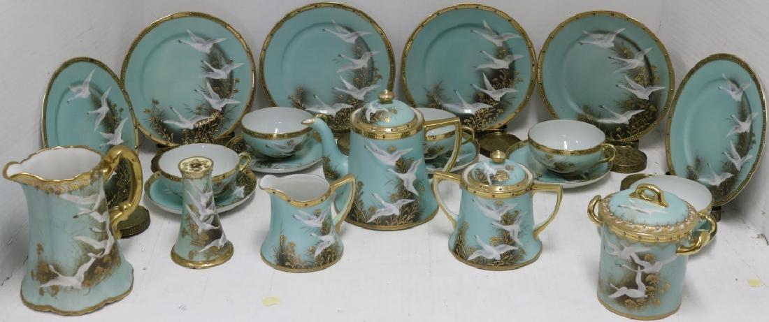 22 PC. NIPPON DESSERT SET WITH GILT AND ENAMEL,: FLYING CRANES DECORATION, 1920'S. INCLUDES 6 DESSERT PLATES, 5 CUP & SAUCERS, 6 1/2" HIGH TEA POT, 6" HIGH PITCHER, 5" SUGAR BOWL, 4" CREAMER, 5 1/2" JAM JAR, 4 1/2" HAT PIN HOLDER. ALONG WITH 6 BRASS