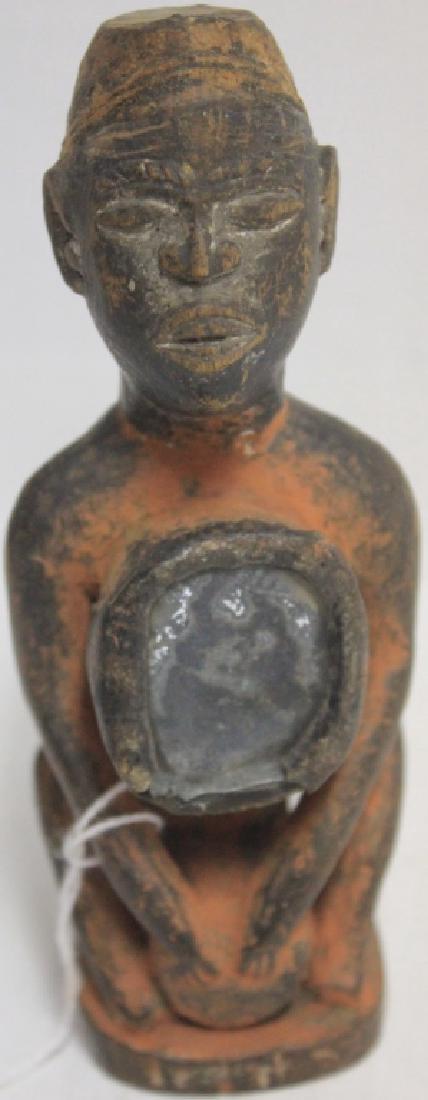 EARLY 19TH C AFRICAN CARVING, POSSIBLY YORUBA: TRIBE DEPICTING A MAN PLAYING A DRUM WITH MIRROR ON HIS CHEST. TRACES OF OLD SALMON PAINT. RARE DIMINUTIVE SIZE 5 1/4" HIGH. PROVENANCE: FAIRHAVEN COLONIAL CLUB.