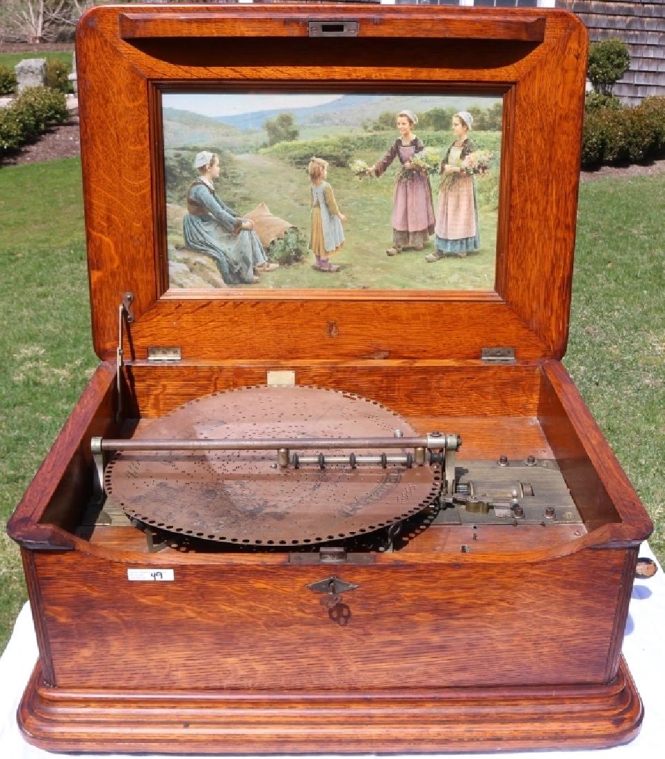 REGINA DOUBLE COMB MUSIC BOX, QUARTER SAWN OAK: CASE. INTERIOR HAS A COLORED LITHOGRAPH DEPICTING DUTCH GIRLS. 15 1/2" DISC. WORKING. 13 1/2" HIGH, 26 1/2" WIDE, 19 1/2" DEEP. ORIGINAL KEY AND CRANK. THIS BOX MAY HAVE BEEN MANUFACTURED BY MIRA NOT 