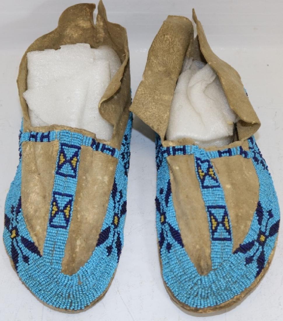 POSSIBLY LATE 19TH CENTURY PAIR OF PLAINS INDIAN: BEADED MOCCASINS WITH BLUE AND YELLOW BEADS IN A GEOMETRIC DESIGN; 9" LONG; GOOD CONDITION.