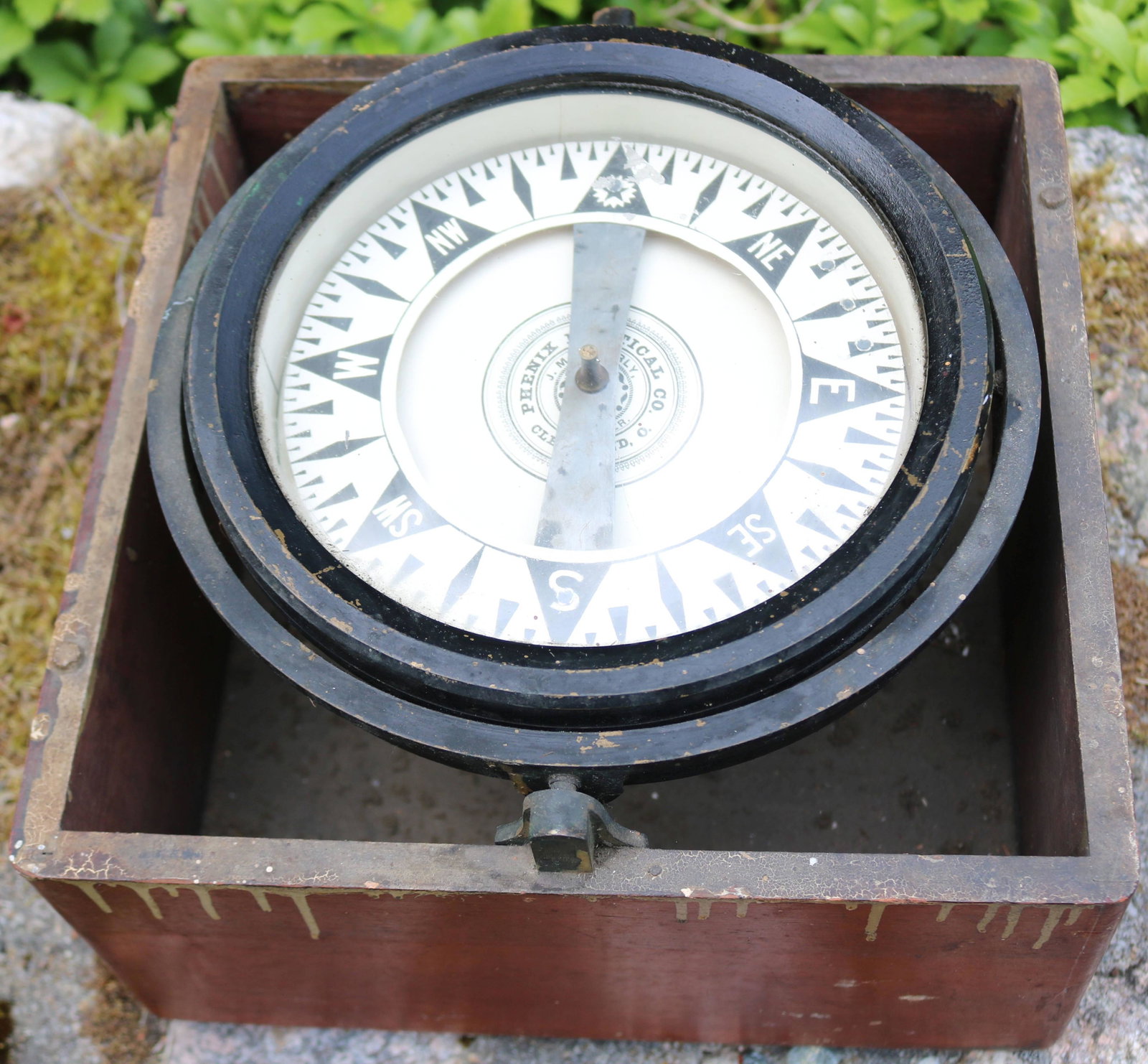 PHOENIX NAUTICAL CO, CLEVELAND, OH, SHIPS COMPASS: MOUNTED IN A MAHOGANY CASE. MISSING ITS LID. WORKING BUT SHOWS PAINT STAINING ON THE CASE. 6 1/2" X 11" X 11".