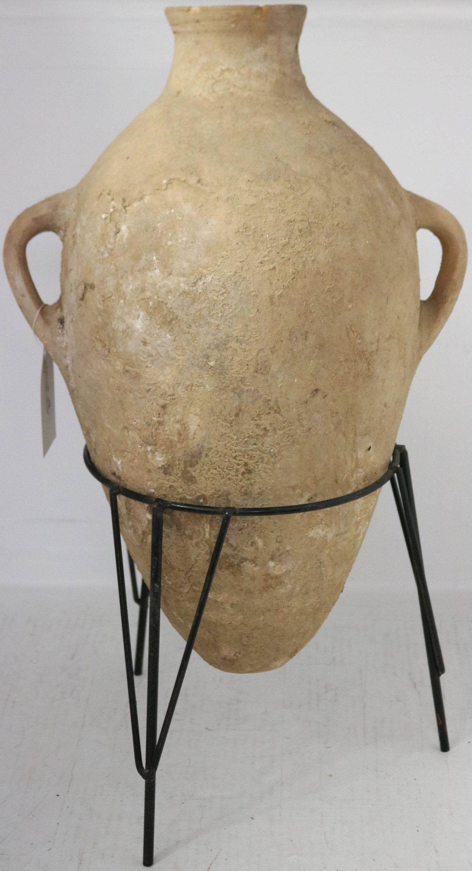 ANCIENT ROMAN AMPHORA VASE, POSSIBLY 200-300 AD.: APPEARS TO BE FROM A SHIP WRECK. TWO HANDLES, OVERALL GOOD CONDITION. SLIGHT CHIPS TO RIM, IN WOODEN STAND. 20" HIGH, 14" WIDE, 10 1/2" DIAMETER. PROVENANCE, ESTATE OF SIR ROBERT MARX.