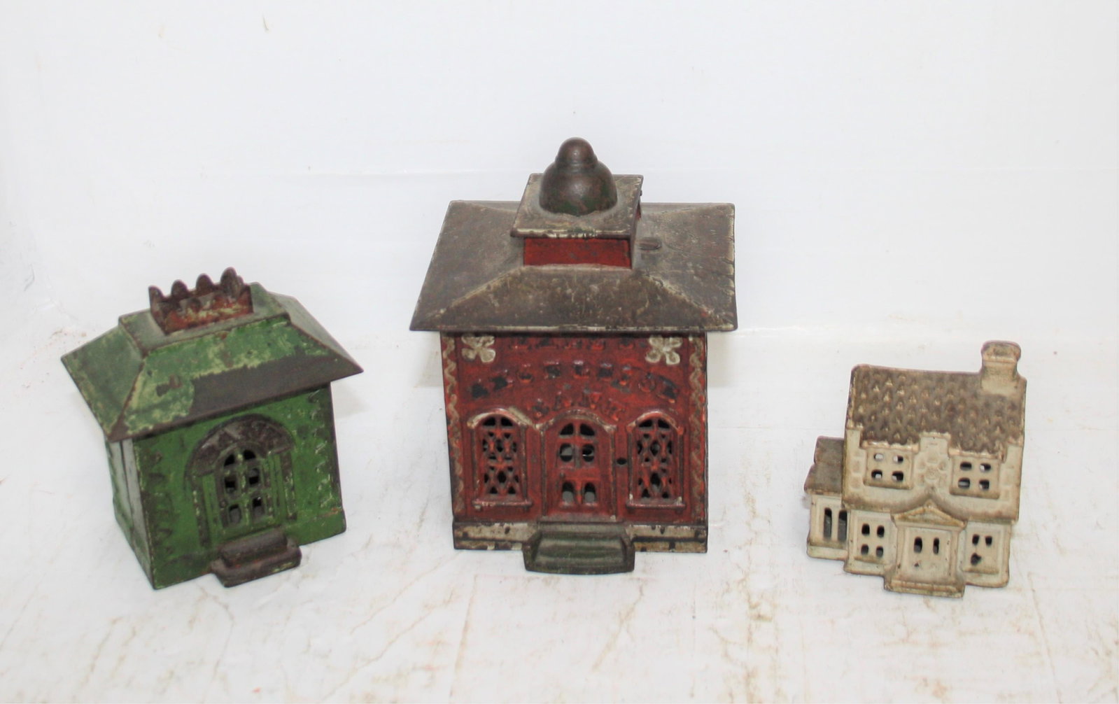 3 CAST IRON STILL BANKS, LATE 19TH CENTURY: TO INCLUDE, HALL'S EXCELSIOR BANK, LIFT-TOP, IN NICE ORIGINAL RED PAINT, GREEN STEPS, WHITE TRIM, 5 1/2" HIGH, 4" WIDE, 4" DEEP, POSSIBLY MISSING A MAN FROM THE LIFT-TOP SECTION. A GREEN BANK IN GOOD 