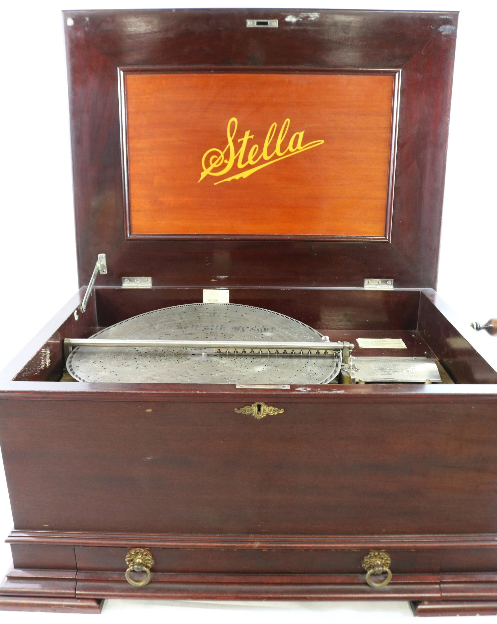 LARGE MAHOGANY STELLA MUSIC BOX WITH TWENTY-ONE: 17 1/4" DISCS THAT PLAY VARIOUS TUNES. DISK STORAGE DRAWER ON BASE. SERIAL #5733. CURRENTLY IN WORKING CONDITION. ONLY ONE COMB IS VISIBLE. 4 SMALL MISSING TEETH IN THE COMB. ORIGINAL FINISH. ORIGINAL
