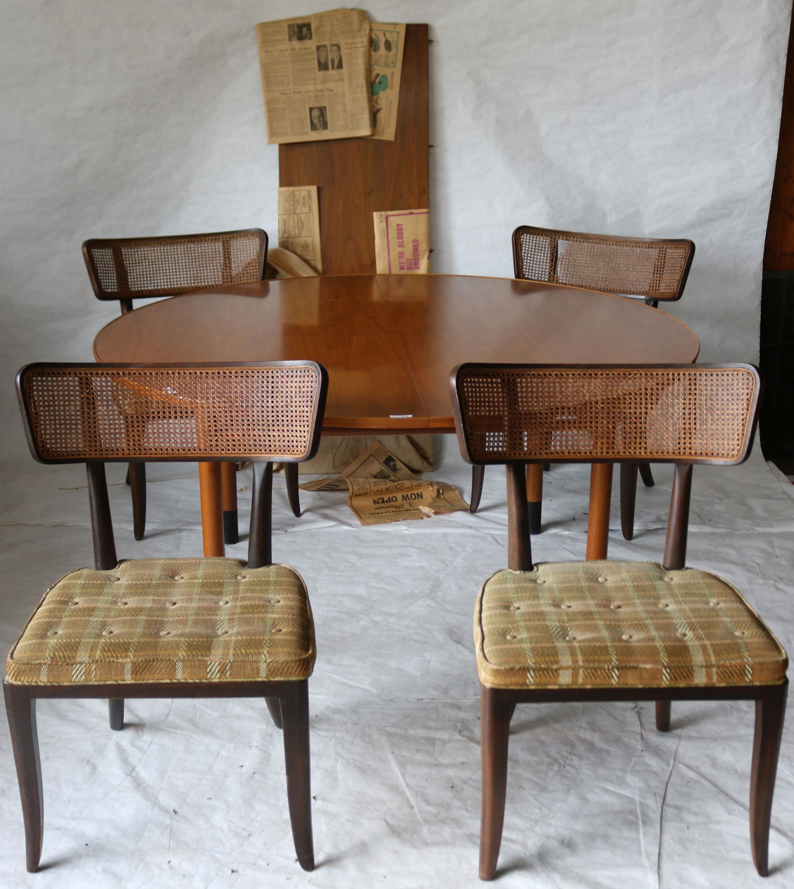 DUNBAR 5 PIECE MID-CENTURY DINING SET. ROUND: DISH-TOP TABLE WITH ONE LEAF, AMBER MAHOGANY, ROUND LEGS WITH METAL CUP FEET, 29 1/2" HIGH, 60" DIAMETER, 20" LEAF WHICH IS WRAPPED IN 1966 NEWSPAPER. COMES WITH ORIGINAL TABLE PADS ALONG WITH FOUR CA
